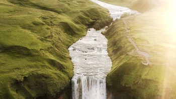 Cahaya keemasan matahari yang menerangi air terjun di tengah padang rumput. Istimewa/dok. Bored Panda/@joelfriend  