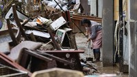 Seorang warga membersihkan rumahnya usai diterjang banjir.
