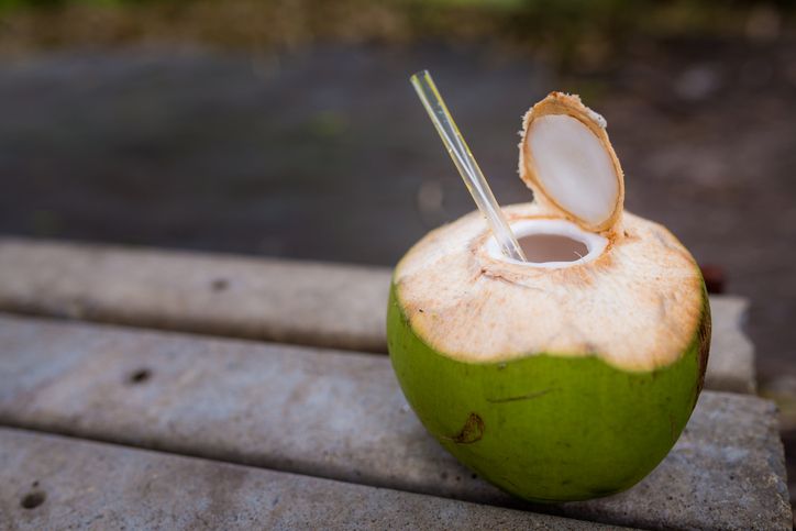 Tropical green coconuts opened for the drinking water with straws.