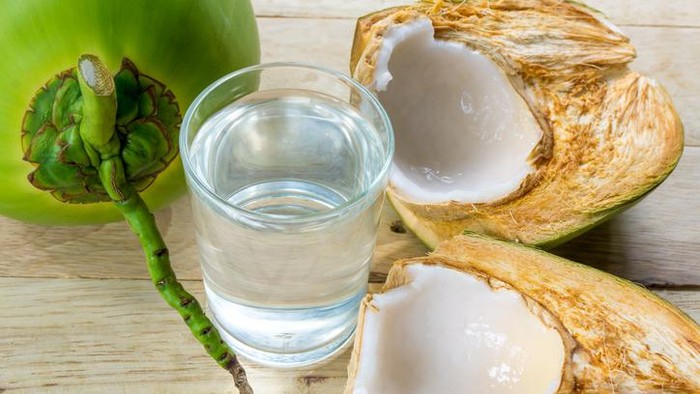 Tropical green coconuts opened for the drinking water with straws.