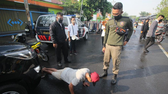 Petugas Satpol PP menghukum warga yang tidak mengenakan masker untuk 'push up' saat Operasi Patuh Masker di Jalan Nyamplungan, Surabaya, Jawa Timur, Senin (6/7/2020). Operasi yang digelar Pemkot Surabaya dan pihak kepolisian setempat itu guna mendisiplinkan warga untuk patuh terhadap protokol kesehatan pencegahan penularan COVID-19. ANTARA FOTO/Didik Suhartono/wsj.
