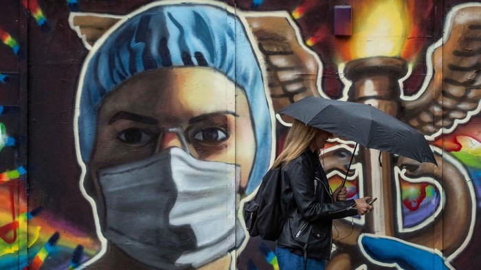 Pekerja Seni Inggris LONDON, ENGLAND - JUNE 11: A woman holding an umbrella walks past a mural of a woman wearing a mask in Shoreditch on June 11, 2020 in London, England. As the British government further relaxes Covid-19 lockdown measures in England, this week sees preparations being made to open non-essential stores and Transport for London handing out face masks to commuters. International travelers arriving in the UK will face a 14-day quarantine period. (Photo by Dan Kitwood/Getty Images) (Photo by Dan Kitwood/Getty Images)