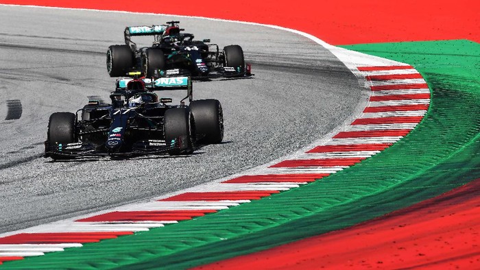 SPIELBERG, AUSTRIA - JULY 05: Valtteri Bottas of Finland and Mercedes GP celebrates with a team member on the podium during the Formula One Grand Prix of Austria at Red Bull Ring on July 05, 2020 in Spielberg, Austria. (Photo by Leonhard Foeger/Pool via Getty Images)