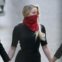 Amber Heard yang belum lama ini diterpa gosip threesome bersama Elon Musk dan model Cara Delevingne muncul dalam balutan blus dan rok serba hitam. Ia menggunakan scarf merah yang dililit di sekitaran wajah sebagai masker. (Foto: AP Photo/Alastair Grant)