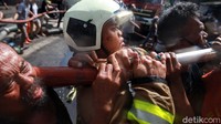 Petugas dibantu warga menggotong selang-selang air dalam proses pemadaman kebakaran.