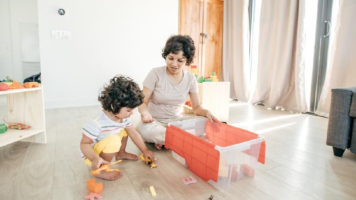 Mom and son putting the toys in the box.