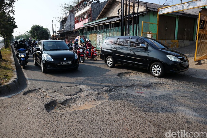 Pengendaran melewati jalan rusak di Jalan I Gusti Ngurah Rai, Bintara, Kota Bekasi, Jawa Barat, Rabu (8/7/2020). Jalan penghubung kota Bekasi dan Jakarta di beberapa titik mengalami kerusakan. Salah satunya di Jalan I Gusti Ngurah Rai, tepatnya di RT 006 RW 014, Kelurahan Bintara, Bekasi Barat, Jawa Barat. Jalan disini berlubang cukup dalam yang mengharuskan pengendara berhati-hati. Kerusakan ini disebabkan buruknya drainase dikawasan tersebut. Kerusakan sudah terjadi sejak bulan Januari hingga kini tidak ada perbaikan.