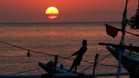 Nelayan beraktivitas diatas kapal saat matahari terbenam di dermaga Penarukan, Situbondo, Jawa Timur, Selasa (7/7/2020).
