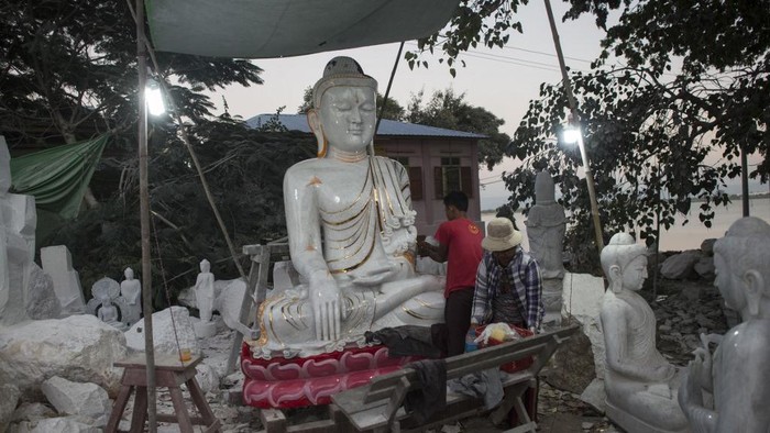 This photo taken on December 22, 2018 shows workers polishing a Buddha statue in Sagyin village on the banks of the Ayeyerwady River in Madaya township, about 46 kms from Mandalay. - Sagyin village is known for producing marble statues, most of which are sold to Chinese traders, with the rest exported to Thailand, Vietnam and Taiwan. (Photo by YE AUNG THU / AFP)