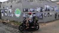 Pengendara motor melintasi foto yang dipamerkan di ruang publik daerah Jati Asih, Bekasi, Jawa Barat, Rabu (8/7/2020).