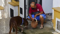 Eros memakan cemilan dari seorang pelanggan atas jasanya membawakan sekeranjang makanan dari pasar El Porvenir.