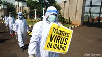 Selain memakai hazmat, mereka juga membawa sejumlah poster. Salah satu poster bertuliskan Terinfeksi Virus Oligarki.
