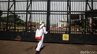 Seorang aktivis menyemprotkan vaksin oligarki di gerbang gedung DPR.