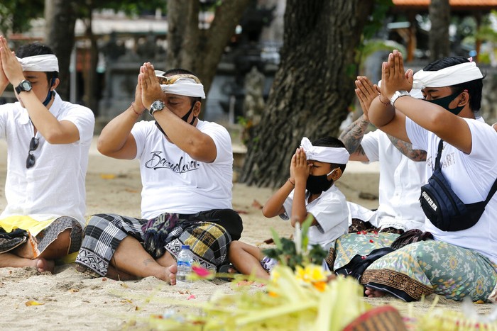 Orang-orang menyaksikan matahari terbit di sebuah pantai di Bali, Indonesia, Kamis (9/7/2020). Pulau resort di Bali dibuka kembali setelah tiga bulan terkunci akibat pandemi virus Corona pada Kamis ini. Pembukaan tahap pertama ini hanya untuk wisatawan dan penduduk lokal serta sebagian turis asing yang terdampar untuk melanjutkan kegiatan publik sebelum kembali dibuka untuk kedatangan orang asing pada September mendatang. (Foto AP / Firdia Lisnawati)