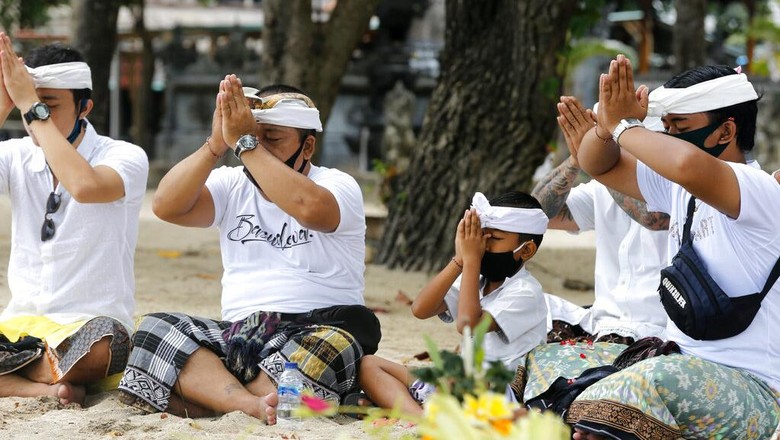 Bali kembali di buka untuk Umum Orang-orang menyaksikan matahari terbit di sebuah pantai di Bali, Indonesia, Kamis (9/7/2020). Pulau resort di Bali dibuka kembali setelah tiga bulan terkunci akibat pandemi virus Corona pada Kamis ini. Pembukaan tahap pertama ini hanya untuk wisatawan dan penduduk lokal serta sebagian turis asing yang terdampar untuk melanjutkan kegiatan publik sebelum kembali dibuka untuk kedatangan orang asing pada September mendatang. (Foto AP / Firdia Lisnawati)