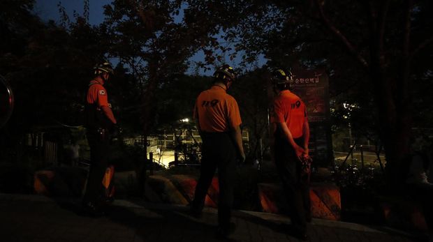 Members of rescue team stand in front of a park in Seoul, South Korea, Thursday, July 9, 2020. Police say Seoul Mayor Park Won-soon has been reported missing and search operations are underway. (AP Photo/Lee Jin-man)