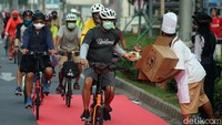 Berdandan ala chef resto bintang 5, mereka membagikan makanan dan minuman untuk pesepeda yang melintas di Jl Sudirman, Jakarta Selatan. (Foto Rengga Sancaya/detikHealth)
