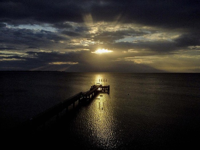 The rising sun is seen between clouds over the pier of Scharbeutz at the Baltic Sea, Germany, Monday, July 6, 2020. (AP Photo/Michael Probst)