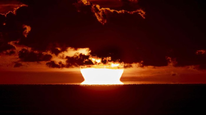 The rising sun is seen between clouds over the pier of Scharbeutz at the Baltic Sea, Germany, Monday, July 6, 2020. (AP Photo/Michael Probst)