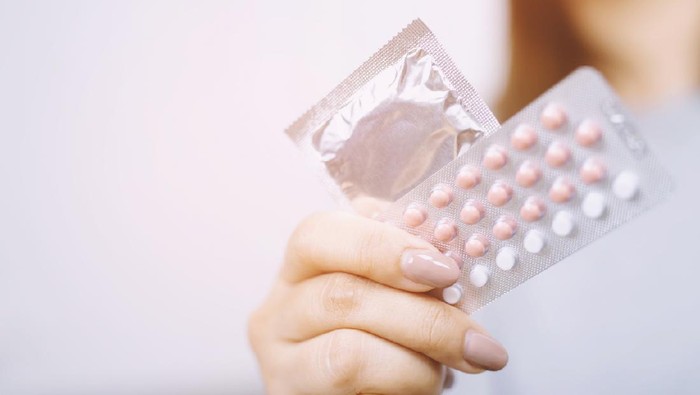 Close up hand contraceptive pill and condom on with colorful pills strips. Contraception reduces childbirth and pregnant concept.