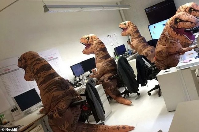 Kalau kamu menemukan yang seperti ini di ruang kerjamu, kira-kira apa yang akan kamu lakukan? Bukan patung, tapi ini adalah foto karyawan yang sedang merayakan Halloween dengan menggunakan kostum dinosaurus. Foto: dok. Reddit