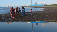 Pengunjung bermain dipantai Bohay dengan latar belakang PLTU Paiton di Probolinggo, Jawa Timur, Selasa (7/7/2020). ANTARA FOTO/Budi Candra Setya.