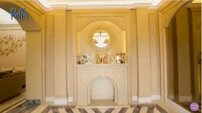 Setelah melihat area luar, Prilly lalu memperlihatkan bagian dalam rumahnya. Diawali dengan sebuah foyer yang disebut Prilly sebagai wall of fame room. Di sini, Prilly memajang sejumlah penghargaan yang pernah diraihnya. Rumah itu kan first impression sangat penting. Jadi saya bikin foyer ini, pandangan pertama langsung teringat. Jadi saya pikir ini tempat yang tepat, pandangan pertama apa yang Prilly achieve, kata sang desainer interior, Figuramas Dityo. Ia juga menjelaskan, pola lantai marmer yang geometris dipilih untuk merepresentasikan karakter Prilly yang edgy dan berjiwa muda. (Foto: YouTube/Prilly Latuconsina)
