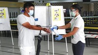Usai melakukan pemilihan suara, tangan warga pun akan disemprotkan cairan disinfektan oleh petugas bersiaga. AP Photo.