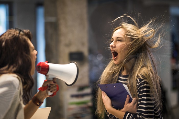 Rude female leader yelling at her coworker through megaphone.