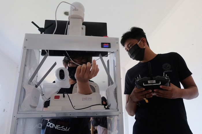 Mahasiswa memeriksa tekanan darah dengan menggunakan robot rakitan saat melakukan uji coba di ruang Unit Kegiatan Mahasiswa (UKM) Robotec Universitas Udayana, Denpasar, Bali, Jumat (10/7/2020). Robot hasil karya mahasiswa Teknik Elektro dan Teknik Mesin tersebut dilengkapi alat untuk memeriksa tekanan darah, suhu tubuh dan tempat pengiriman makanan maupun obat-obatan bagi pasien sehingga ditargetkan dapat membantu tugas tenaga medis yang berisiko tinggi dalam menangani penderita COVID-19. ANTARA FOTO/Nyoman Hendra Wibowo/nym/wsj.