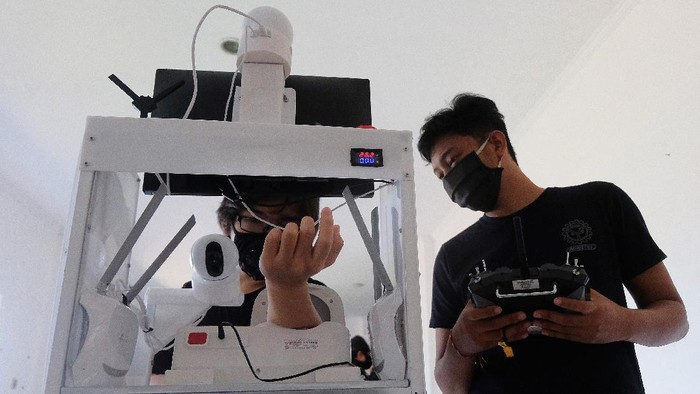 Mahasiswa memeriksa tekanan darah dengan menggunakan robot rakitan saat melakukan uji coba di ruang Unit Kegiatan Mahasiswa (UKM) Robotec Universitas Udayana, Denpasar, Bali, Jumat (10/7/2020). Robot hasil karya mahasiswa Teknik Elektro dan Teknik Mesin tersebut dilengkapi alat untuk memeriksa tekanan darah, suhu tubuh dan tempat pengiriman makanan maupun obat-obatan bagi pasien sehingga ditargetkan dapat membantu tugas tenaga medis yang berisiko tinggi dalam menangani penderita COVID-19. ANTARA FOTO/Nyoman Hendra Wibowo/nym/wsj.