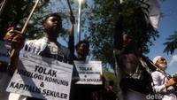 Peserta aksi terlihat berjalan kaki dengan membawa poster dan spanduk penolakan RUU HIP.