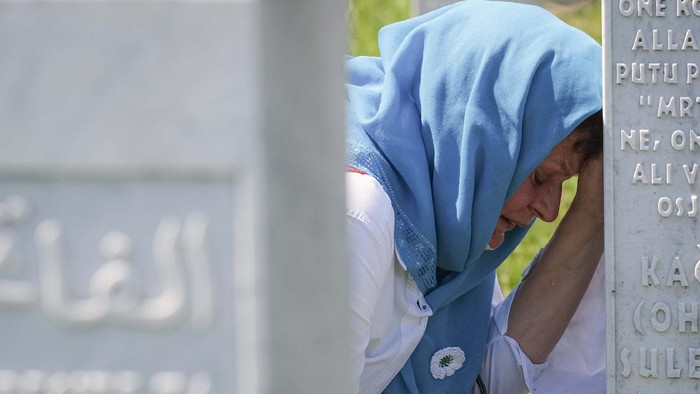 Mengenang 25 Tahun Pembantaian Srebrenica Women lean on a gravestone in Potocari, near Srebrenica, Bosnia, Saturday, July 11, 2020. Nine newly found and identified men and boys were laid to rest as Bosnians commemorate 25 years since more than 8,000 Bosnian Muslims perished in 10 days of slaughter, after Srebrenica was overrun by Bosnian Serb forces during the closing months of the country's 1992-95 fratricidal war, in Europe's worst post-WWII massacre. (AP Photo/Kemal Softic)