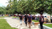 Sebagian besar lainnya duduk-duduk santai di fasilitas taman atau menggelar tikar makan bersama di bawah rindang pepohonan.
