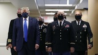 Trump mengenakan masker warna hitam ketika ia berjalan melalui koridor rumah sakit militer Walter Reed di luar Washington, Sabtu (11/7), untuk bertemu dengan para veteran yang terluka.