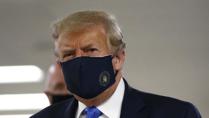Potret Trump Pertama Kalinya Pakai Masker di Depan Umum President Donald Trump, center, wearing a mask as he walks down the hallway during his visit to Walter Reed National Military Medical Center in Bethesda, Md., Saturday, July 11, 2020. (AP Photo/Patrick Semansky)