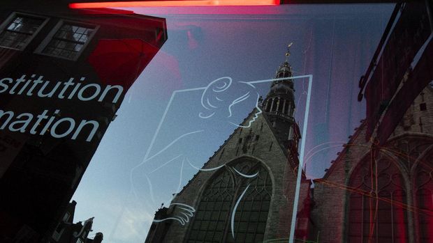 Oude Kerk, or Old Church, is reflected in the window of the PIC, Prostitution Information Center, as sex workers welcomed clients again in the Red Light District in Amsterdam, Netherlands, Wednesday, July 1, 2020. It wasn't quite business as usual as the capital's Red Light District emerged from coronavirus lockdown, but it was as close as it has been since the pandemic slammed the brakes on the world's oldest profession. (AP Photo/Peter Dejong)
