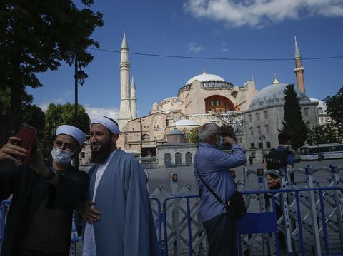 People use their mobile to take a selfie picture outside the now closed Byzantine-era Hagia Sophia, one of Istanbul's main tourist attractions in the historic Sultanahmet district of Istanbul, Saturday, July 11, 2020. Turkey's President Recep Tayyip Erdogan formally reconverted Hagia Sophia into a mosque and declared it open for Muslim worship, hours after a high court annulled a 1934 decision that had made the religious landmark a museum.The decision sparked deep dismay among Orthodox Christians. Originally a cathedral, Hagia Sophia was turned into a mosque after Istanbul's conquest by the Ottoman Empire but had been a museum for the last 86 years, drawing millions of tourists annually. (AP Photo/Emrah Gurel)