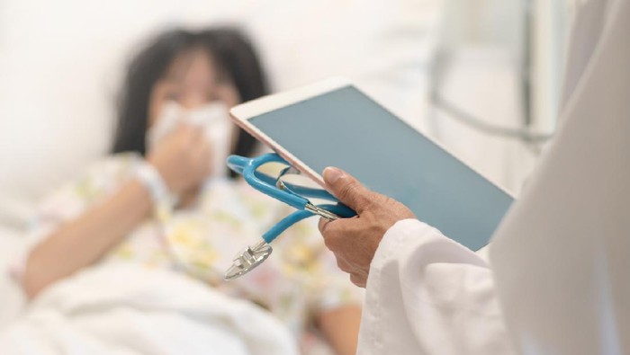 1178239787 Professional general medical pediatrician doctor in white uniform gown visit Asia child patient with stethoscope and tablet computer chart. Physician check up Asian kid female inpatient in hospital children ward.