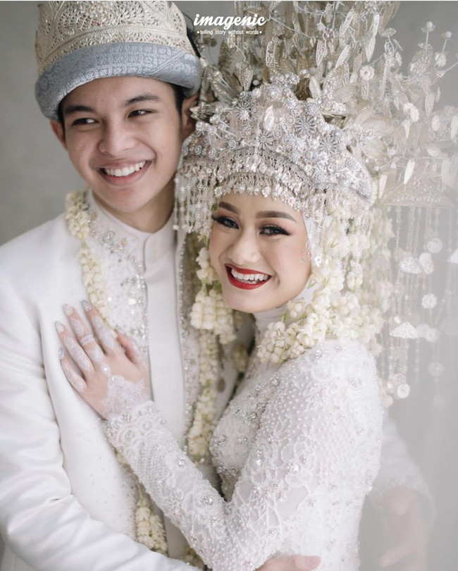 Tiba saat akad nikah pada Jumat (10/7/2020), Dinda Hauw dan Rey Mbayang  mengenakan busana pengantin adat Palembang bernuansa putih. Dinda menggunakan mahkota aesan paksangko, yang juga dihiasi kembang goyang di bagian kepala, kembang kenango, kelapo standan, dan lain-lain. Setelah acara pernikahan ini, pasangan pengantin baru tersebut sempat viral karena pengakuan Dinda yang tak bisa masak mie instant. Foto: Instagram @imagenic.