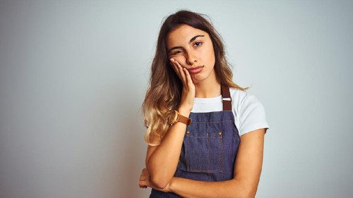 Crying man with pan on head on gray background