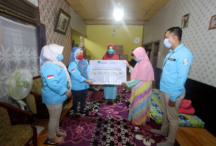 Pencairan Klaim Asuransi AXA Mandiri Perwakilan PT AXA Mandiri Financial Services (AXA Mandiri) Rini (dua kiri) menyerahkan pembayaran klaim asuransi jiwa secara simbolis kepada ahli waris nasabah AXA Mandiri Amaliah (dua kanan) di Banjarmasin, Kalimantan Selatan. Melalui manfaat perlindungan asuransi jiwa tersebut, keluarga yang ditinggalkan dapat terbantu secara finansial untuk terus melanjutkan hidup, ketika tulang punggung keluarga tutup usia. AXA Mandiri telah menyediakan perlindungan asuransi kepada lebih dari satu juta nasabah, serta telah membayarkan klaim dan maanfaat sebesar Rp 5,3 triliun pada tahun 2019 lalu. dok. AXA Mandiri