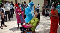 Seorang petugas kesehatan memakai Alat Pelindung Diri (APD) untuk mengambil swab dari seorang wanita untuk menguji Corona (COVID-19) di perumahan daerah Ahmedabad, India.