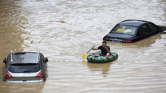 In this photo released by Xinhua News Agency, a man paddles with an inflatable boat past submerged cars during a flood in Rongshui County in southern Chinas Guangxi Zhuang Autonomous Region, Saturday, July 11, 2020. Vice Minister of Emergency Management Zheng Guoguang told reporters Monday, July 13, 2020 that the Yangtze River and parts of its watershed have seen the second highest rainfall since 1961 over the past six months. (Long Linzhi/Xinhua via AP)
