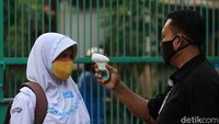 Para siswa harus menjalani rangkaian pemeriksaan seperti cek suhu tubuh sebelum memasuki sekolah, Senin (13/7/2020).