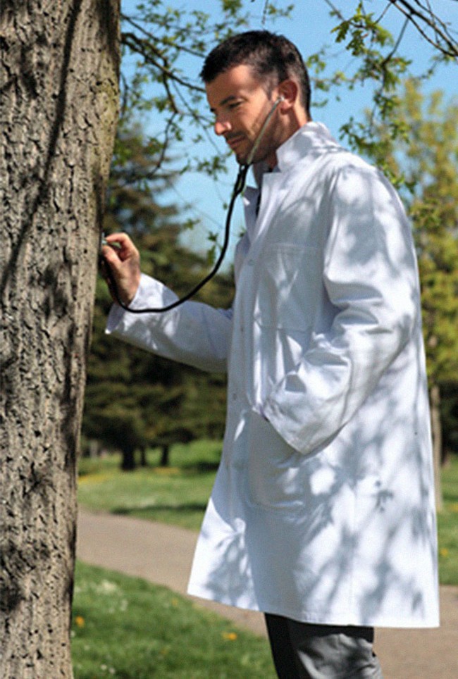 Dengan jas dokter dan stetoskop, model pria ini benar-benar terlihat seperti dokter sungguhan. Tapi tunggu dulu, kenapa dia memeriksa batang pohon menggunakan stetoskop ya? Foto: Twitter