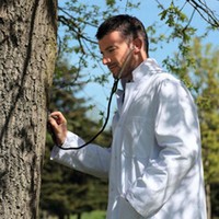 Dengan jas dokter dan stetoskop, model pria ini benar-benar terlihat seperti dokter sungguhan. Tapi tunggu dulu, kenapa dia memeriksa batang pohon menggunakan stetoskop ya? Foto: Twitter