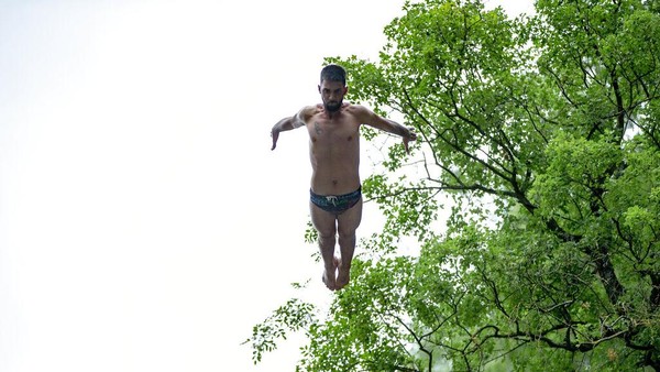 Seorang peserta melompat dari tebing air mancur saat mengikuti kompetisi ekstrem yang digelar di Kosovo tersebut.