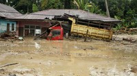 Lumpur yang terbawa arus banjir bandang juga merendam rumah dan truk.