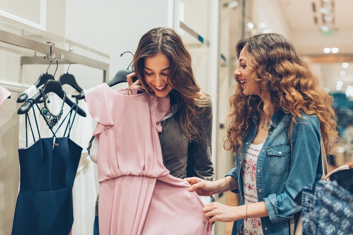 Ilustrasi memilih baju Two young women choosing dresses in a luxury fashion store